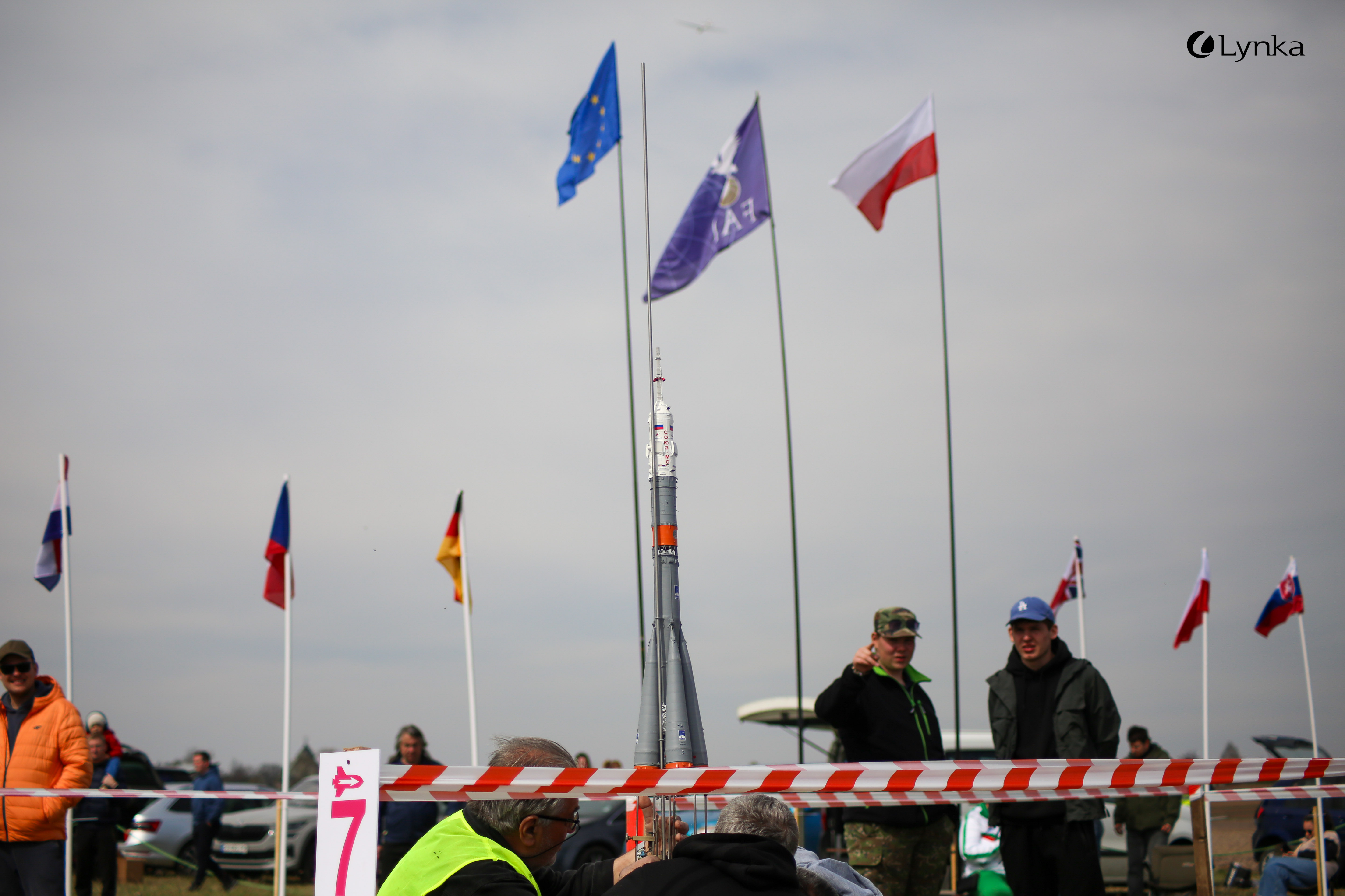 Model rocket on a launch pad against a background of various national and organizational flags during the MTSR 2026 competition.