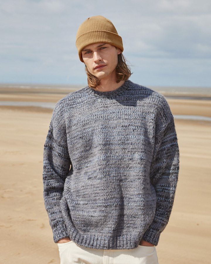 Czapki beanies do nadruku lub haftu – mężczyzna w swetrze i beanie na plaży.